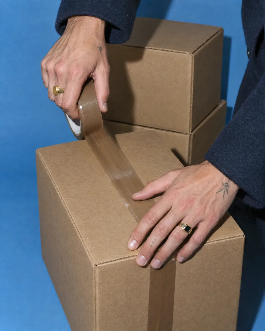 Hands taping a shipping box